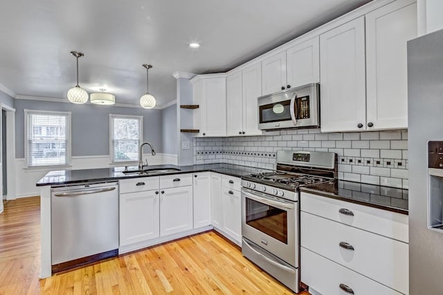 kitchen with white cabinets, crown molding, a sink, stainless steel appliances, and a peninsula