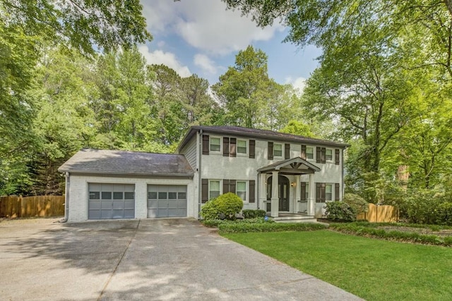 colonial-style house with concrete driveway, an attached garage, fence, and a front lawn