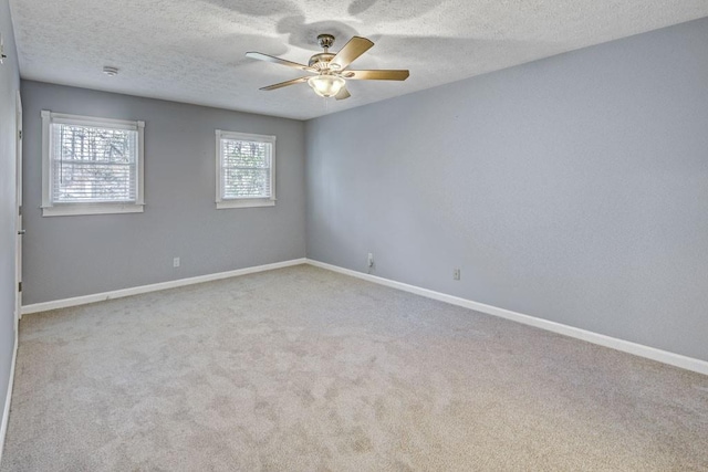 carpeted empty room featuring baseboards, ceiling fan, and a textured ceiling