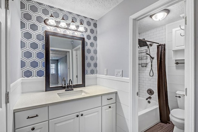 bathroom with vanity, wainscoting, toilet, a textured ceiling, and shower / bath combo