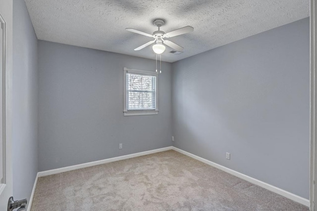 carpeted spare room featuring a textured ceiling, ceiling fan, visible vents, and baseboards