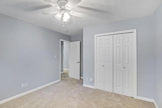 unfurnished bedroom with carpet floors, a textured ceiling, baseboards, and a closet