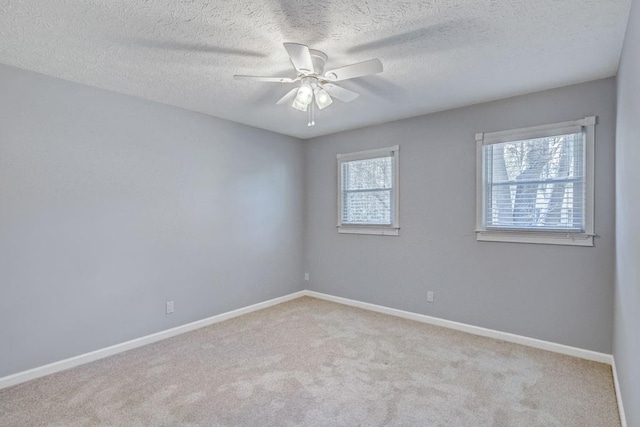 unfurnished room with baseboards, carpet, a ceiling fan, and a textured ceiling