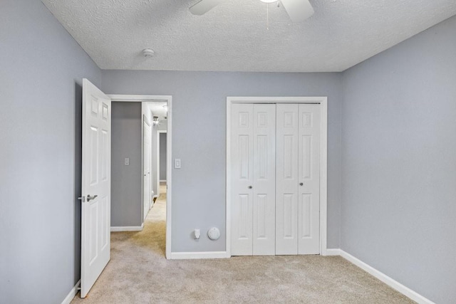 unfurnished bedroom featuring carpet flooring, a textured ceiling, baseboards, and a closet