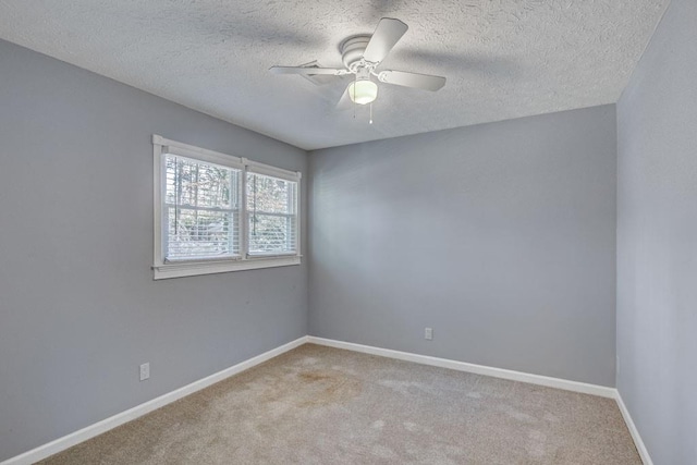 unfurnished room with a ceiling fan, baseboards, light colored carpet, and a textured ceiling