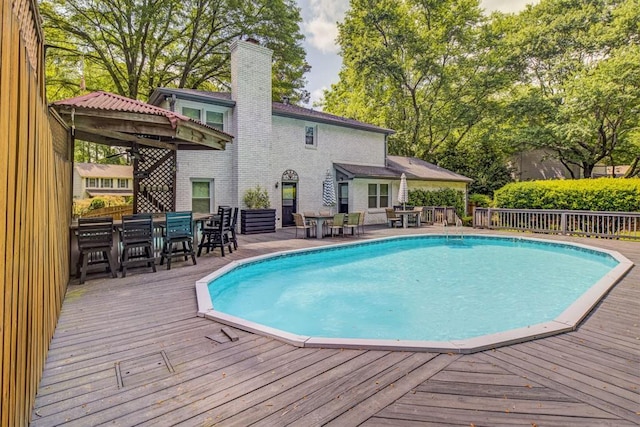 view of swimming pool with a fenced in pool, a wooden deck, and outdoor dining space