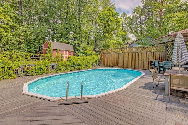 pool with a deck, fence, and outdoor dining space