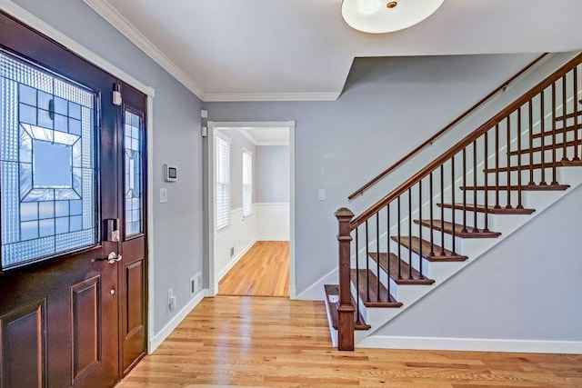 foyer entrance featuring light wood-style floors, ornamental molding, visible vents, and stairway