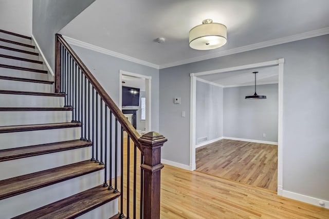 stairs featuring crown molding, baseboards, wood finished floors, and visible vents