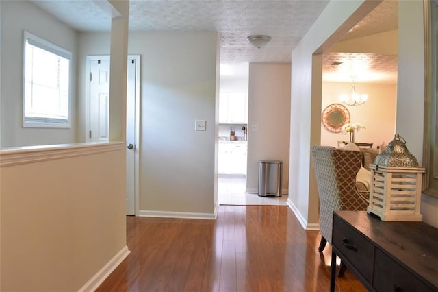 1676 Northridge Dr, Morrow, GA 30260 - hallway featuring baseboards, a chandelier, a textured ceiling, and wood finished floors