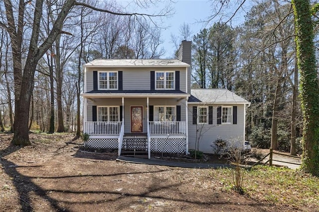 view of front facade featuring covered porch and a chimney