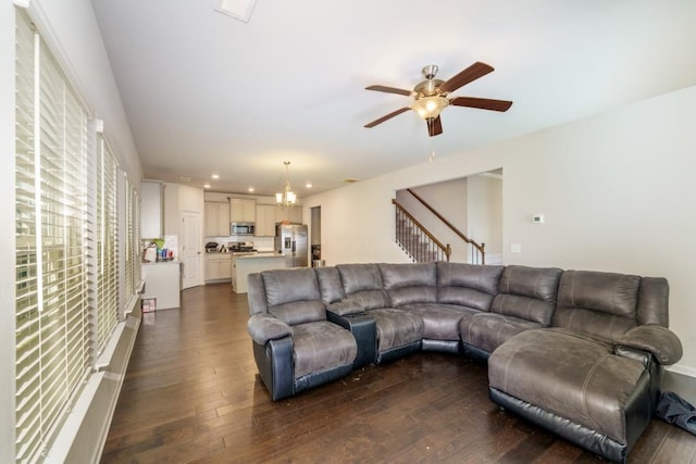 living room featuring ceiling fan with notable chandelier and dark hardwood / wood-style flooring