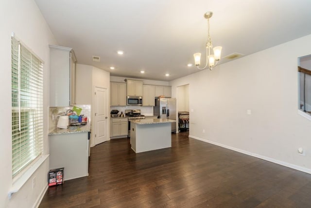 kitchen with pendant lighting, dark wood-type flooring, a kitchen island, light stone counters, and stainless steel appliances