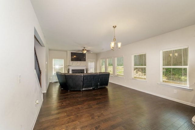 unfurnished living room featuring plenty of natural light, dark wood-type flooring, and ceiling fan with notable chandelier