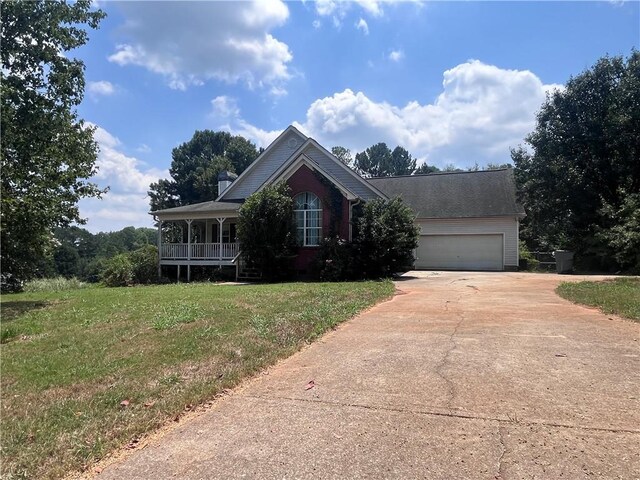 view of front of property featuring a garage, a front lawn, and covered porch