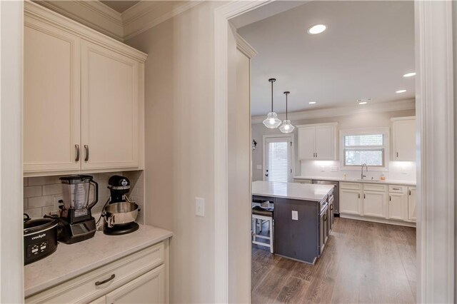 kitchen featuring white cabinetry, sink, ornamental molding, hanging light fixtures, and dark hardwood / wood-style flooring