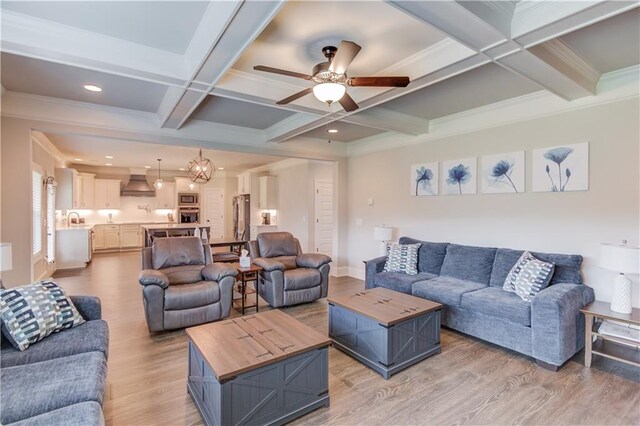 living room with ornamental molding, coffered ceiling, light hardwood / wood-style floors, beamed ceiling, and ceiling fan