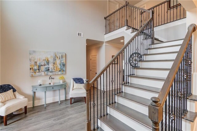 stairway featuring hardwood / wood-style flooring, ornamental molding, and a towering ceiling