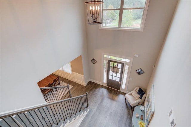 foyer entrance with a high ceiling, wood-type flooring, and an inviting chandelier