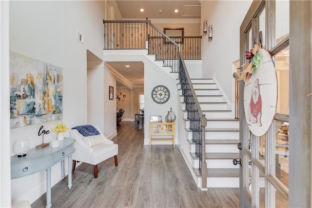 foyer entrance with a high ceiling, hardwood / wood-style floors, and crown molding