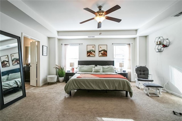 carpeted bedroom featuring multiple windows, a raised ceiling, and ceiling fan