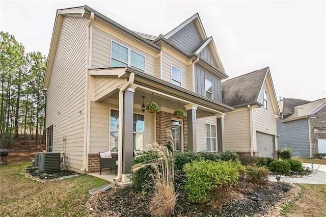view of front of home featuring covered porch, central air condition unit, board and batten siding, and an attached garage