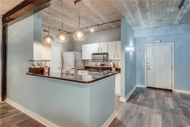 kitchen with white cabinets, hanging light fixtures, hardwood / wood-style flooring, kitchen peninsula, and stainless steel appliances