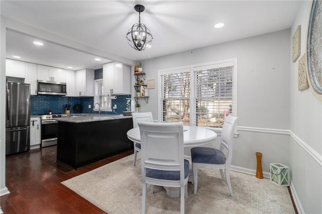 kitchen featuring tasteful backsplash, a peninsula, white cabinets, stainless steel appliances, and dark wood-style flooring