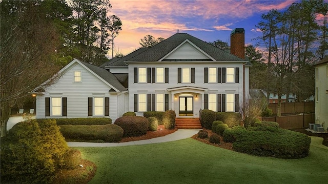 colonial inspired home featuring a lawn and central AC