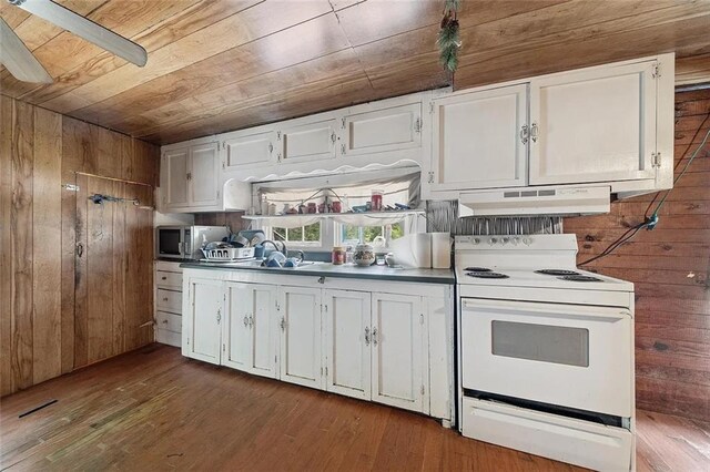 kitchen featuring wood walls, white cabinetry, and electric range