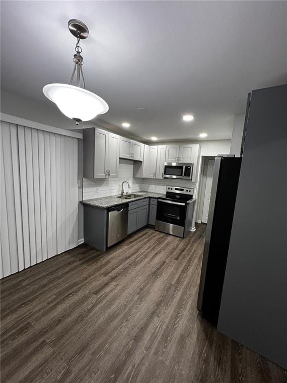 kitchen featuring pendant lighting, dark wood-type flooring, sink, decorative backsplash, and stainless steel appliances