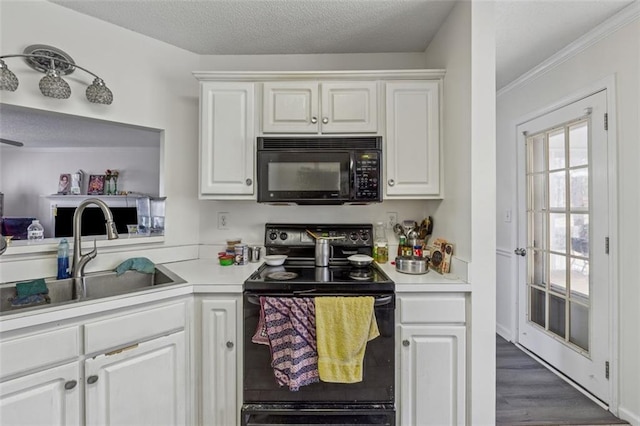 kitchen with black appliances, white cabinets, light countertops, and a sink