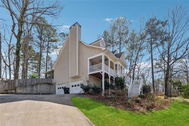 view of property exterior with a ceiling fan, aphalt driveway, fence, stairway, and an attached garage