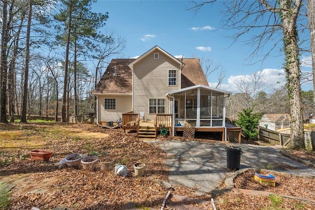 back of house featuring a deck, fence, a sunroom, and roof with shingles