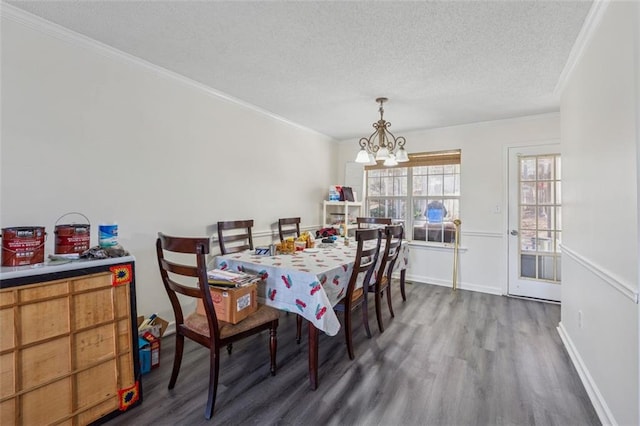 dining space featuring a notable chandelier, ornamental molding, a textured ceiling, wood finished floors, and baseboards