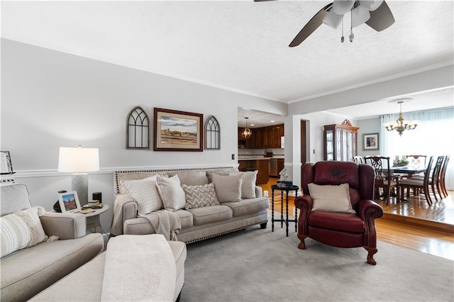 carpeted living room with ceiling fan with notable chandelier and crown molding