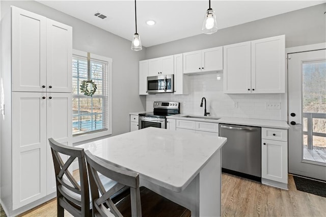 kitchen with appliances with stainless steel finishes, white cabinetry, pendant lighting, and sink