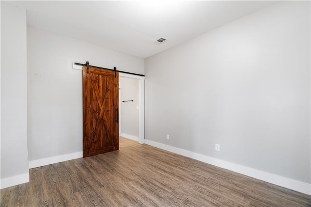 empty room with hardwood / wood-style floors and a barn door