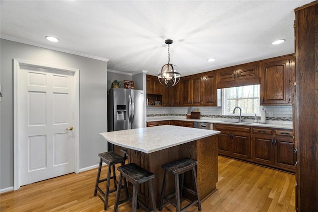 kitchen with a center island, ceiling fan with notable chandelier, ornamental molding, decorative light fixtures, and stainless steel fridge with ice dispenser