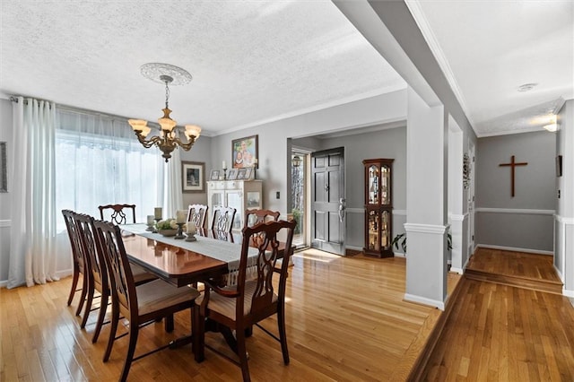 dining room featuring a chandelier, a textured ceiling, light hardwood / wood-style floors, and ornamental molding