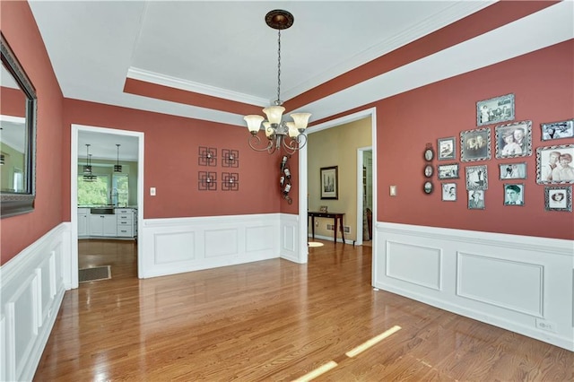 unfurnished room featuring an inviting chandelier, light hardwood / wood-style floors, and ornamental molding