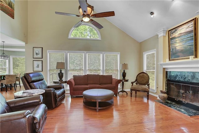 living room featuring light hardwood / wood-style flooring, ceiling fan, a wealth of natural light, and a premium fireplace