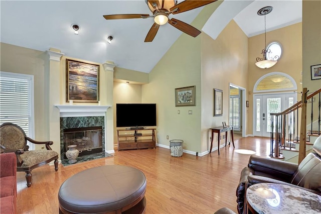 living room with ceiling fan, light wood-type flooring, high vaulted ceiling, and a premium fireplace