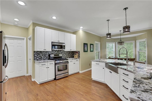 kitchen featuring appliances with stainless steel finishes, white cabinetry, and pendant lighting