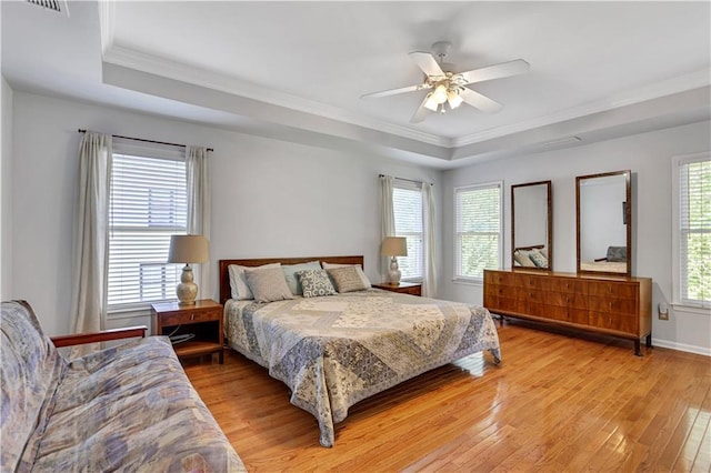 bedroom featuring a tray ceiling, ceiling fan, ornamental molding, and light hardwood / wood-style flooring