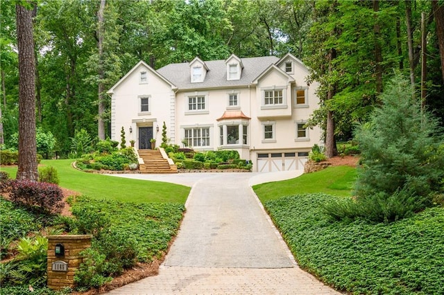 view of front of home with stucco siding, a front lawn, an attached garage, and driveway