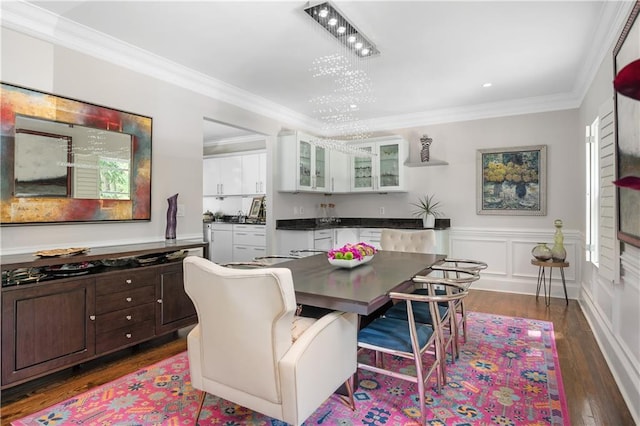 dining space featuring dark wood-type flooring, ornamental molding, wainscoting, and a decorative wall