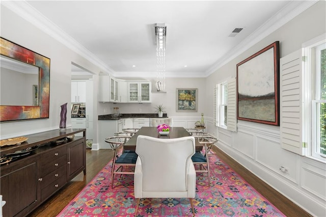 dining area featuring visible vents, dark wood-style flooring, ornamental molding, wainscoting, and a decorative wall