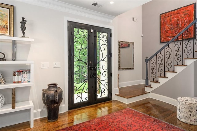 foyer with stairway, wood finished floors, visible vents, ornamental molding, and french doors