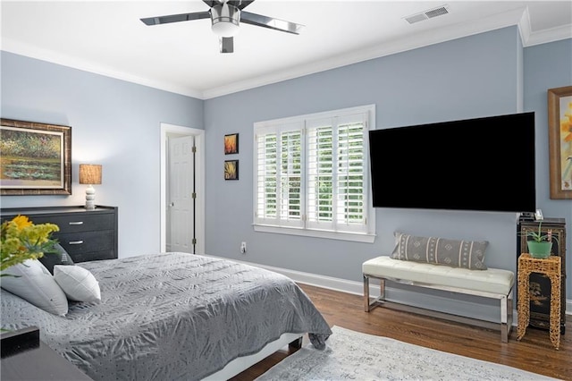 bedroom with a ceiling fan, baseboards, wood finished floors, visible vents, and ornamental molding